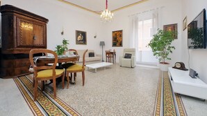 Un vaste salon comprenant un coin repas, un lustre et une grande armoire en bois.