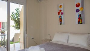 Een hotelkamer met een bed, nachtkastje, stoel en raam met uitzicht.