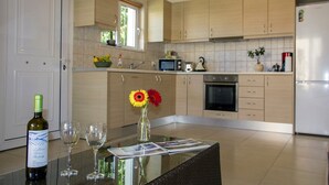 Een moderne keuken met lichte houten kastjes, een RVS-oven en een koelkast.