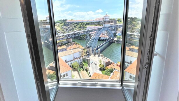 Vista desde una habitación con un ventanal grande que da a un puente y edificios.