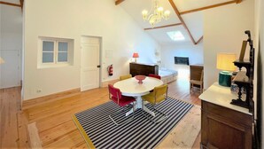 Un espacioso dormitorio tipo loft con techo inclinado, una zona de comedor con una mesa redonda y sillas, y una kitchenette con estufa y fregadero.