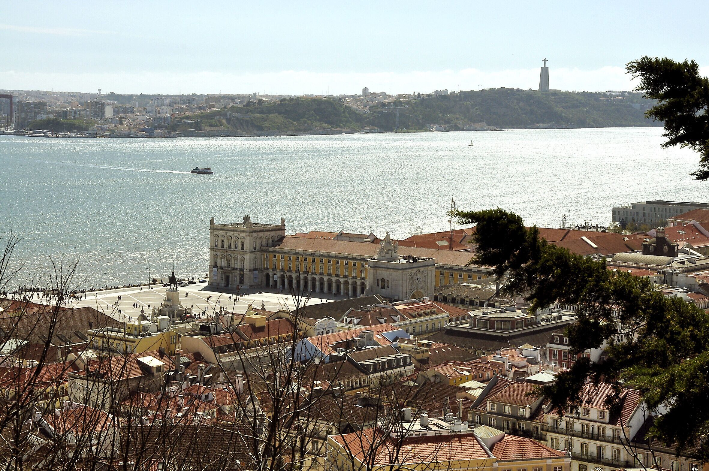 A coastal cityscape with a prominent historical building, a river, and a hilltop church.