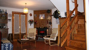 A cozy living room with a fireplace, wooden staircase, and a dining area.