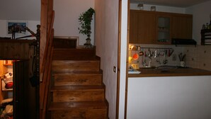 A wooden staircase leading to a kitchen with wooden cabinets and a tiled backsplash.