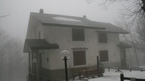 A two-story building with a snow-covered ground, a wooden bench, and a lamp post.