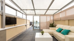 A modern outdoor lounge area with a sofa, a coffee table, and a TV screen. - ApartUP Patacona Terrace Duplex II (Alboraya)