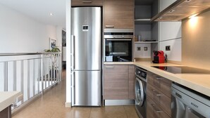A modern kitchen with stainless steel appliances, wooden cabinets, and a dishwasher. - ApartUP Patacona Terrace Duplex II (Alboraya)
