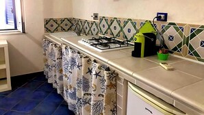 Una cocina con estufa a gas, un lavabo y una ventana con persianas.