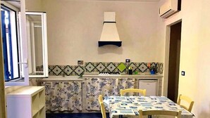 Una cocina funcional con una mesa y sillas, horno integrado y salpicadero de azulejos.
