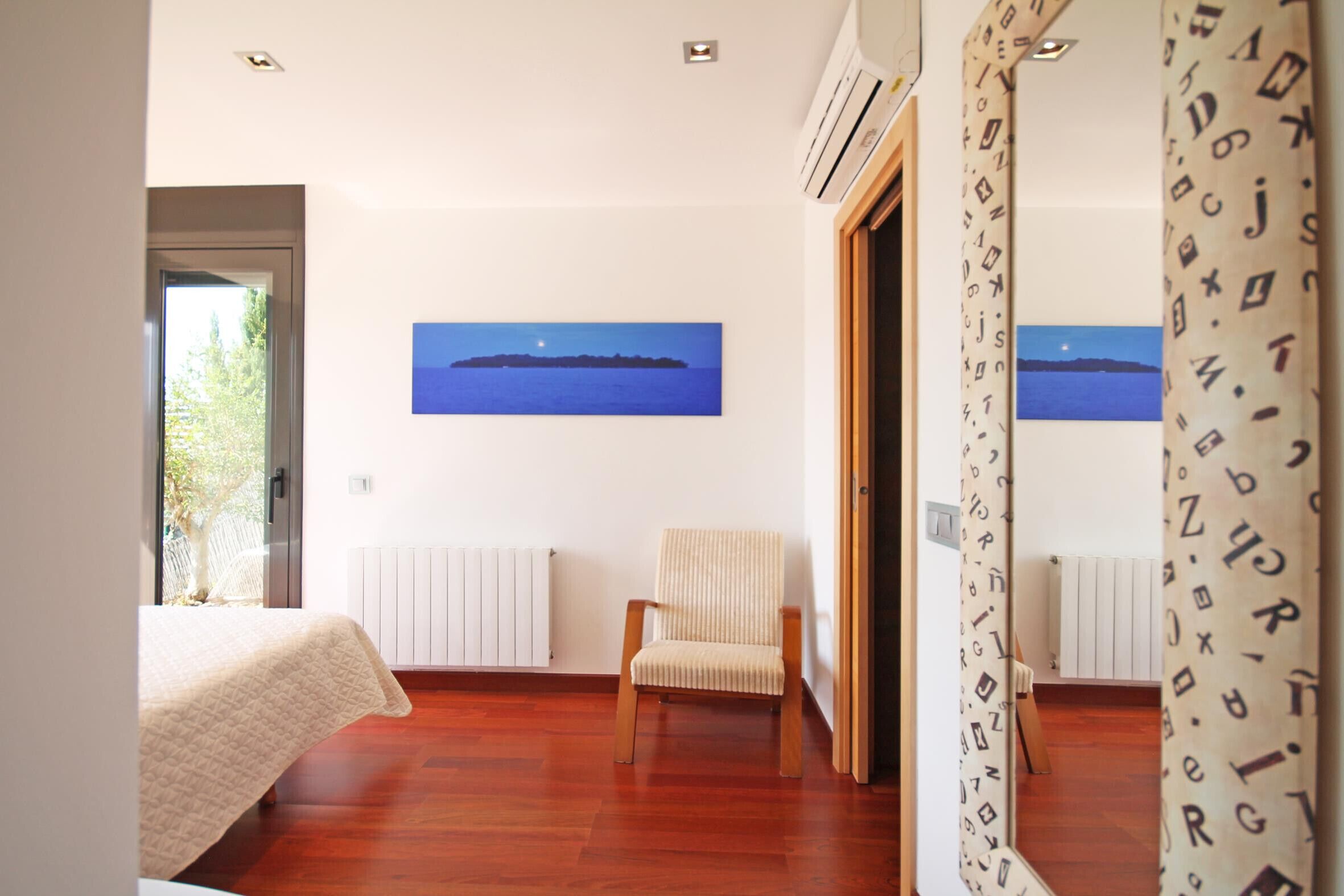 Une chambre à coucher avec un lit, une chaise, un tableau représentant un navire accroché au mur et un radiateur.