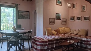 A cozy room with a wooden ceiling, a dining table with chairs, a sofa with patterned cushions, and framed pictures on the walls. - VILLA OLIVI. (Nocchi)