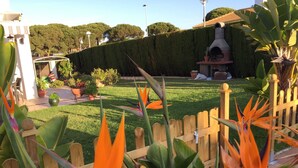 A well-maintained garden with a wooden fence, a lawn, and various potted plants. - Semi-detached house in El Portil with private pool, free wifi, AC, BBQ  (El Portil)