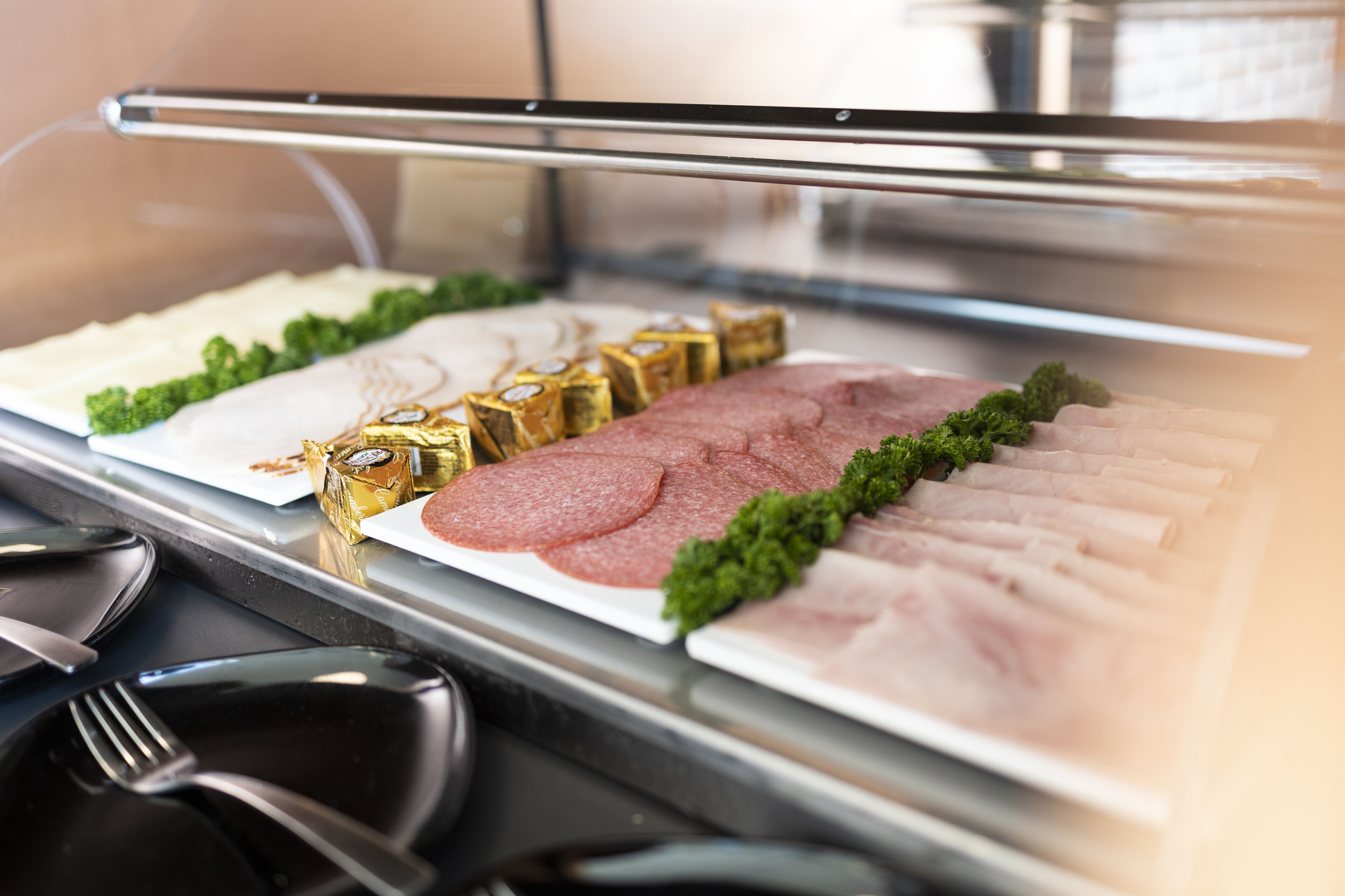 Un buffet proposant une variété de viandes et de fromages en tranches, présentés sur un présentoir en verre.