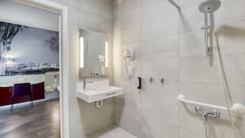 Un baño moderno con ducha, lavamanos y espejo.