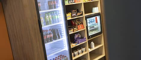 Ein Getränke- und Snackautomat, gefüllt mit Getränken und Snacks, darunter Coca-Cola, Fanta, Mars und weitere Artikel.