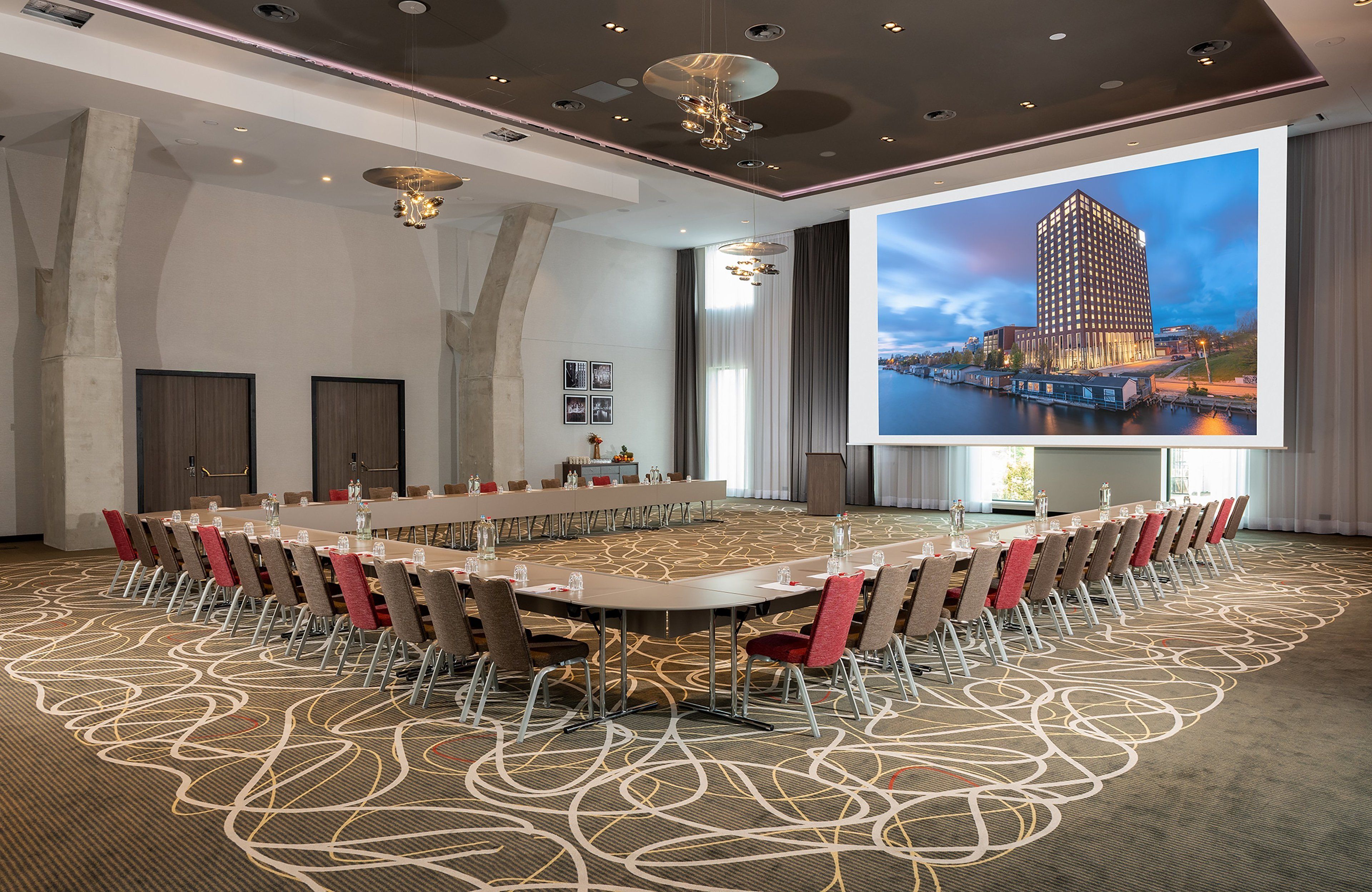 A conference room with a large table, chairs, and a screen displaying a building.