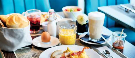 A breakfast table with a variety of food items, including eggs, bacon, and toast, along with beverages and condiments.