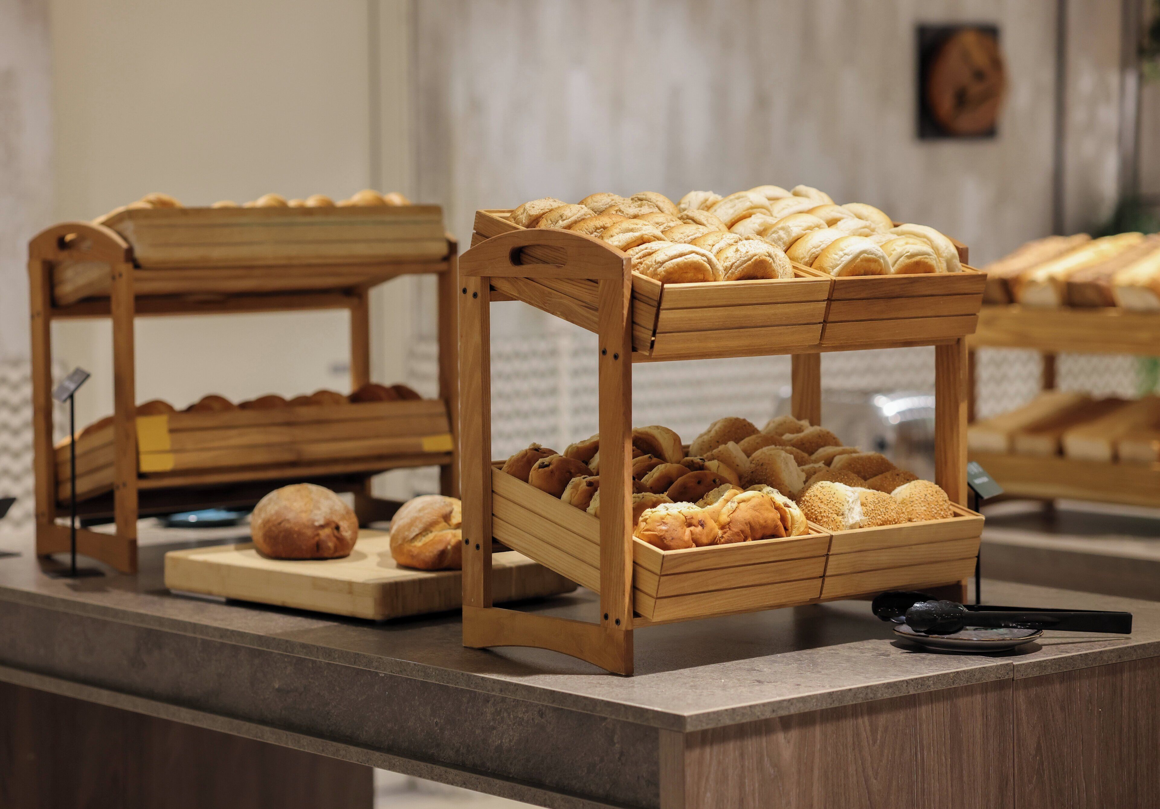 Des paniers à pain en bois sont posés sur un comptoir, accompagnés de diverses sortes de produits de boulangerie.