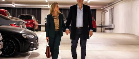 Una pareja camina por un estacionamiento con autos a ambos lados.