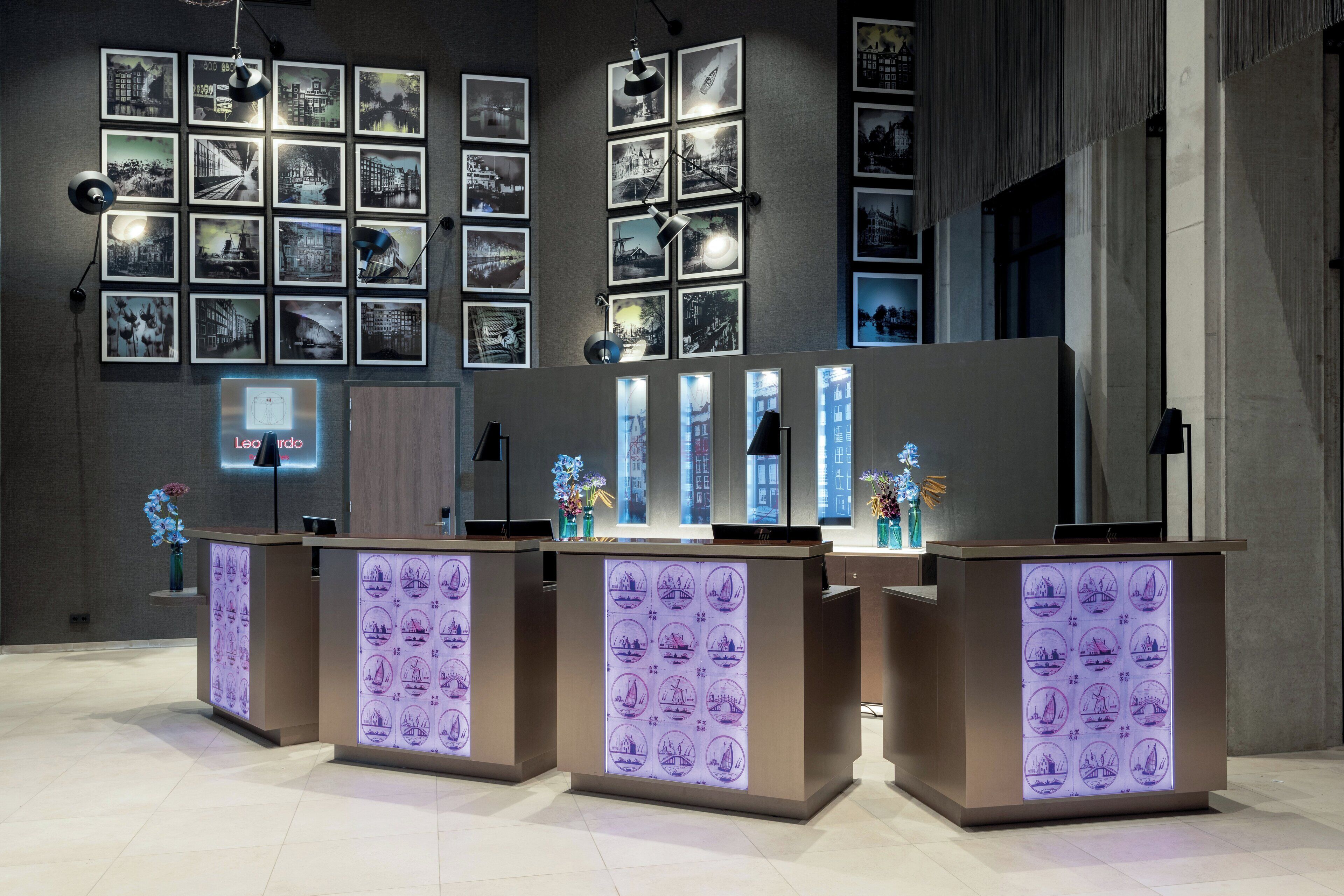 Una zona de recepción de diseño moderno, con una serie de fotografías enmarcadas en la pared y mostradores de recepción iluminados.
