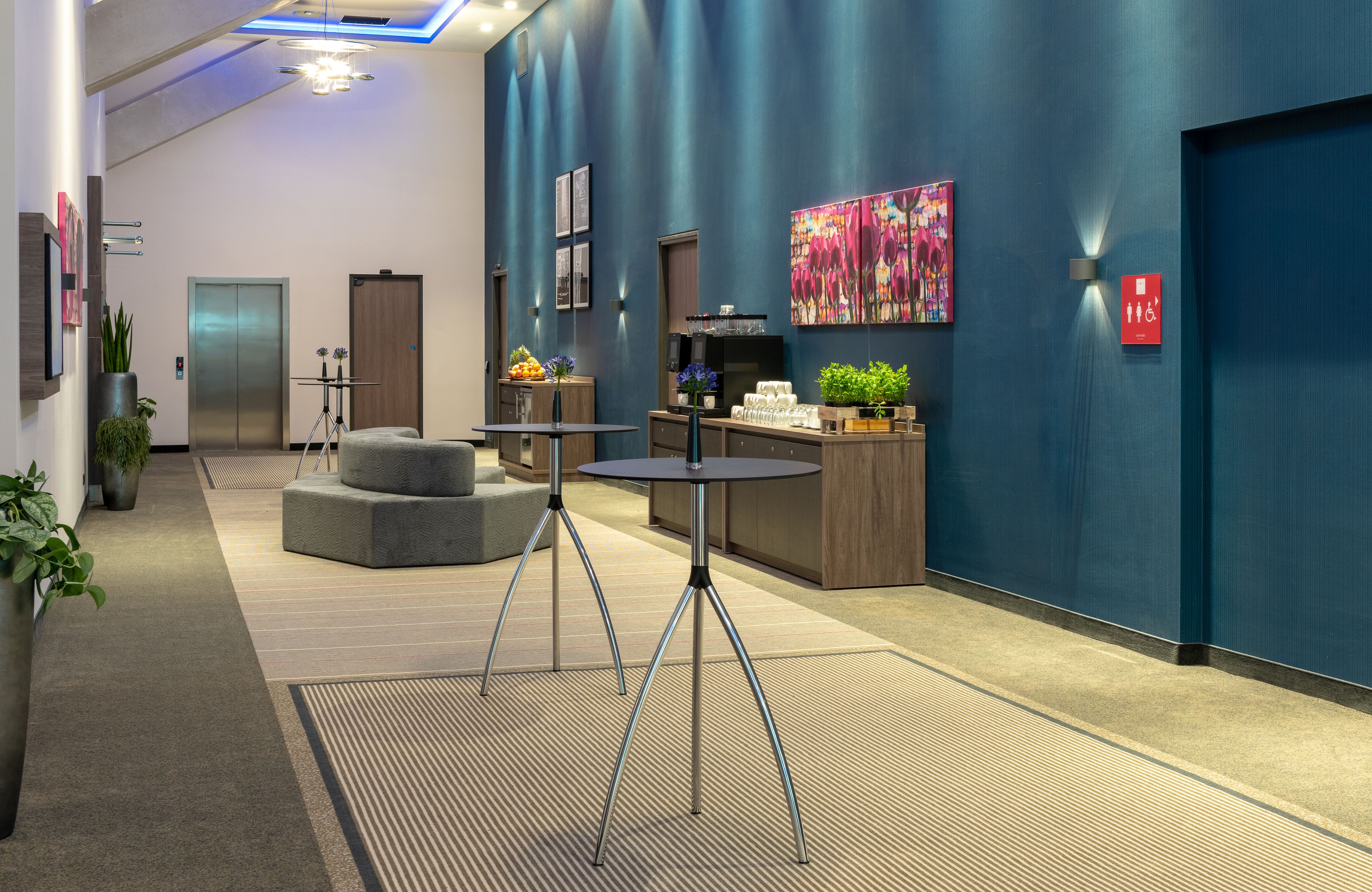A modern lobby with a blue accent wall, a reception desk, a seating area, and a staircase.