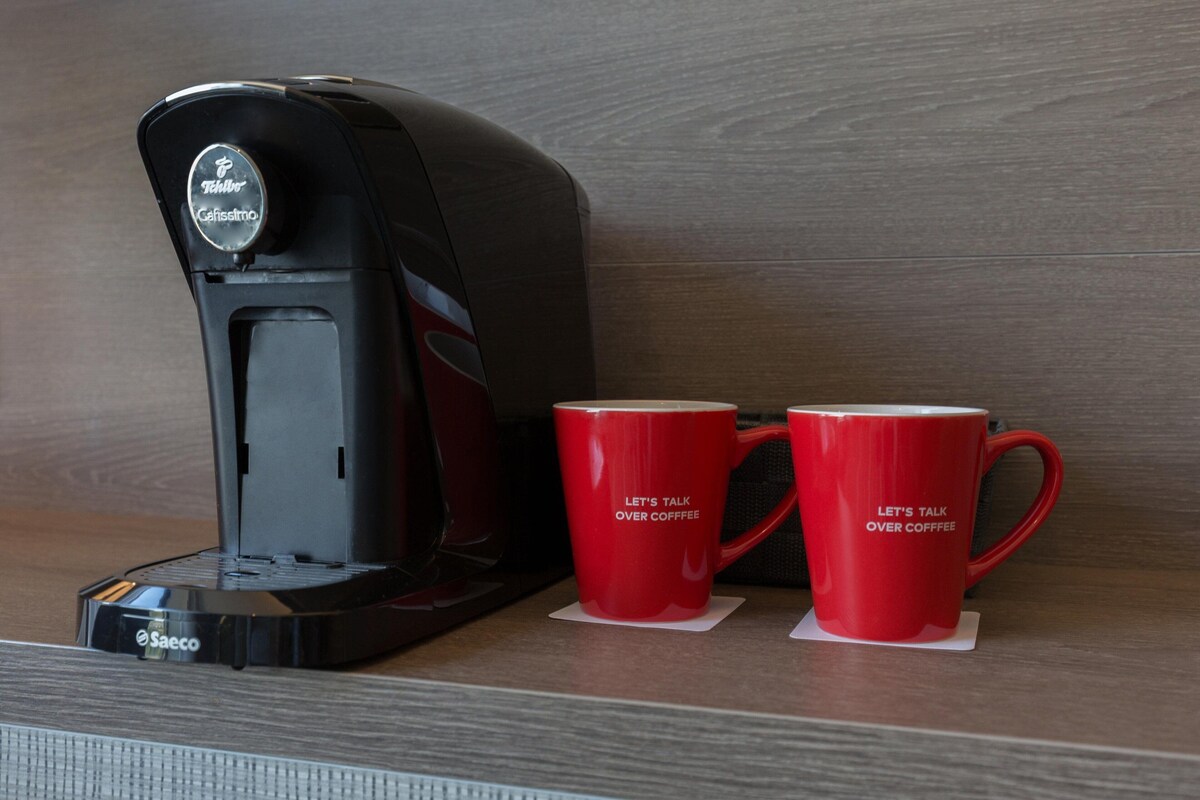 A Keurig coffee maker with two red mugs on a wooden surface.