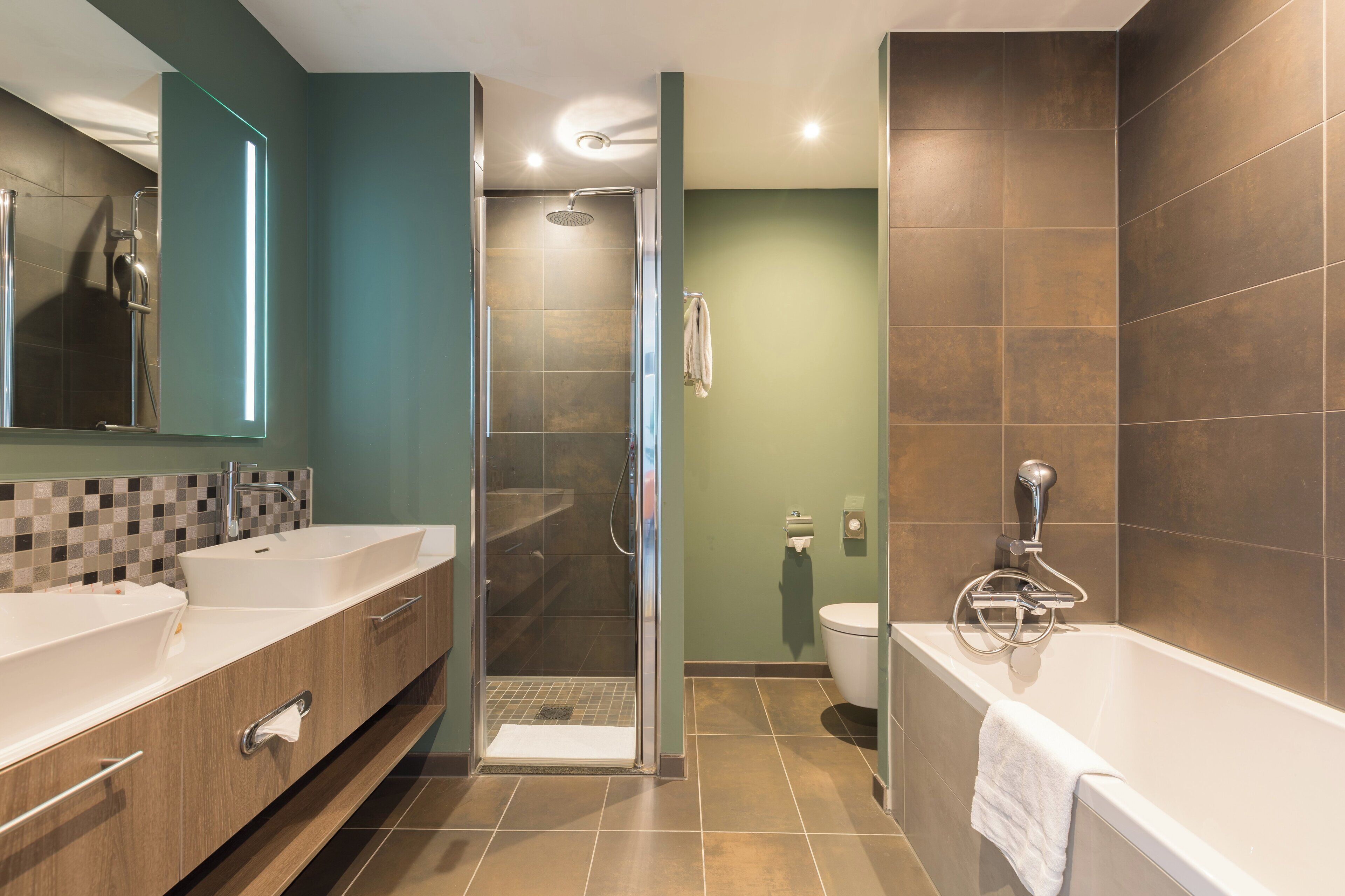 Een moderne badkamer met een ruime douche, een badkuip en een toilet.