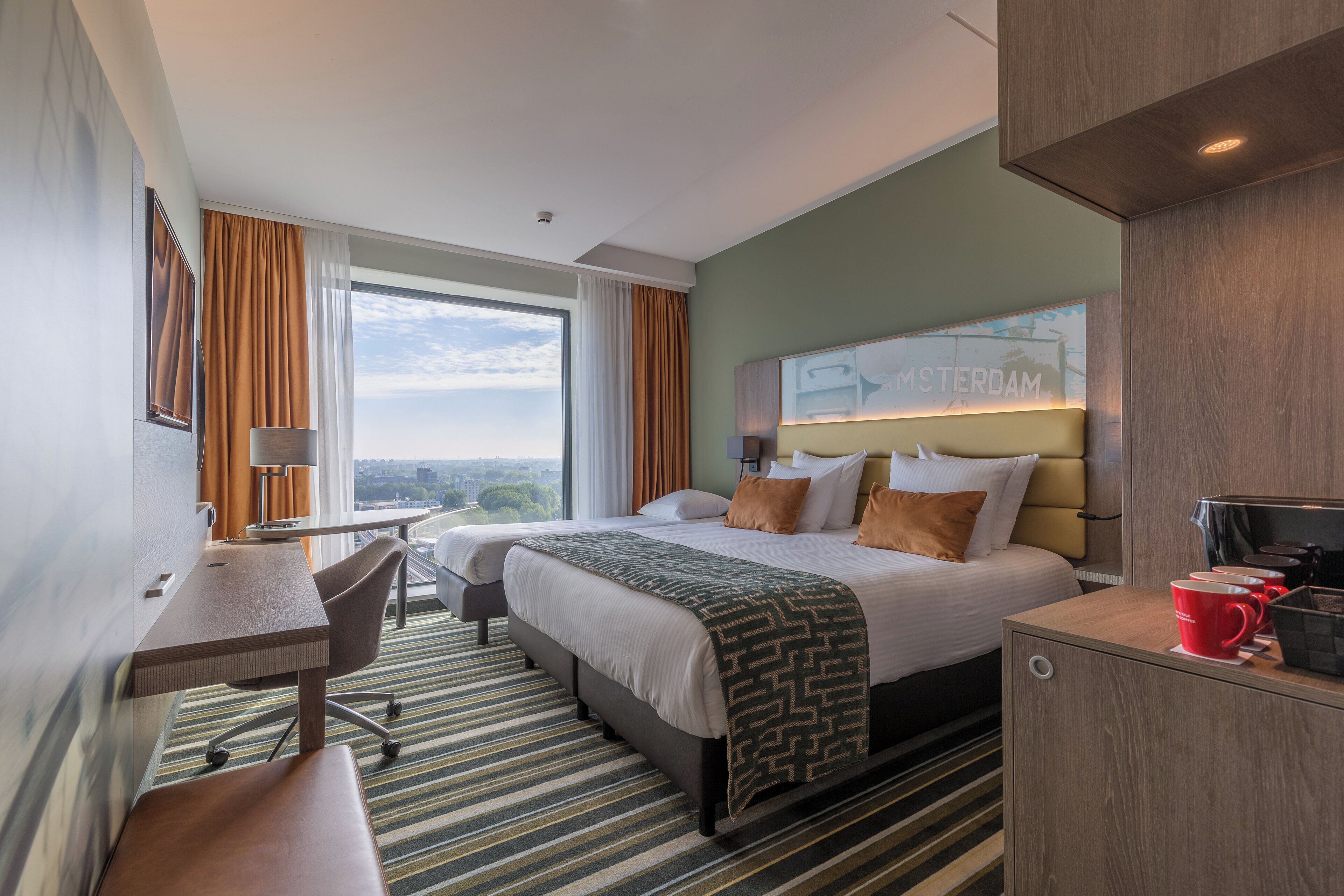 Une chambre d’hôtel avec un grand lit, un bureau, une chaise et une vue sur la ville.