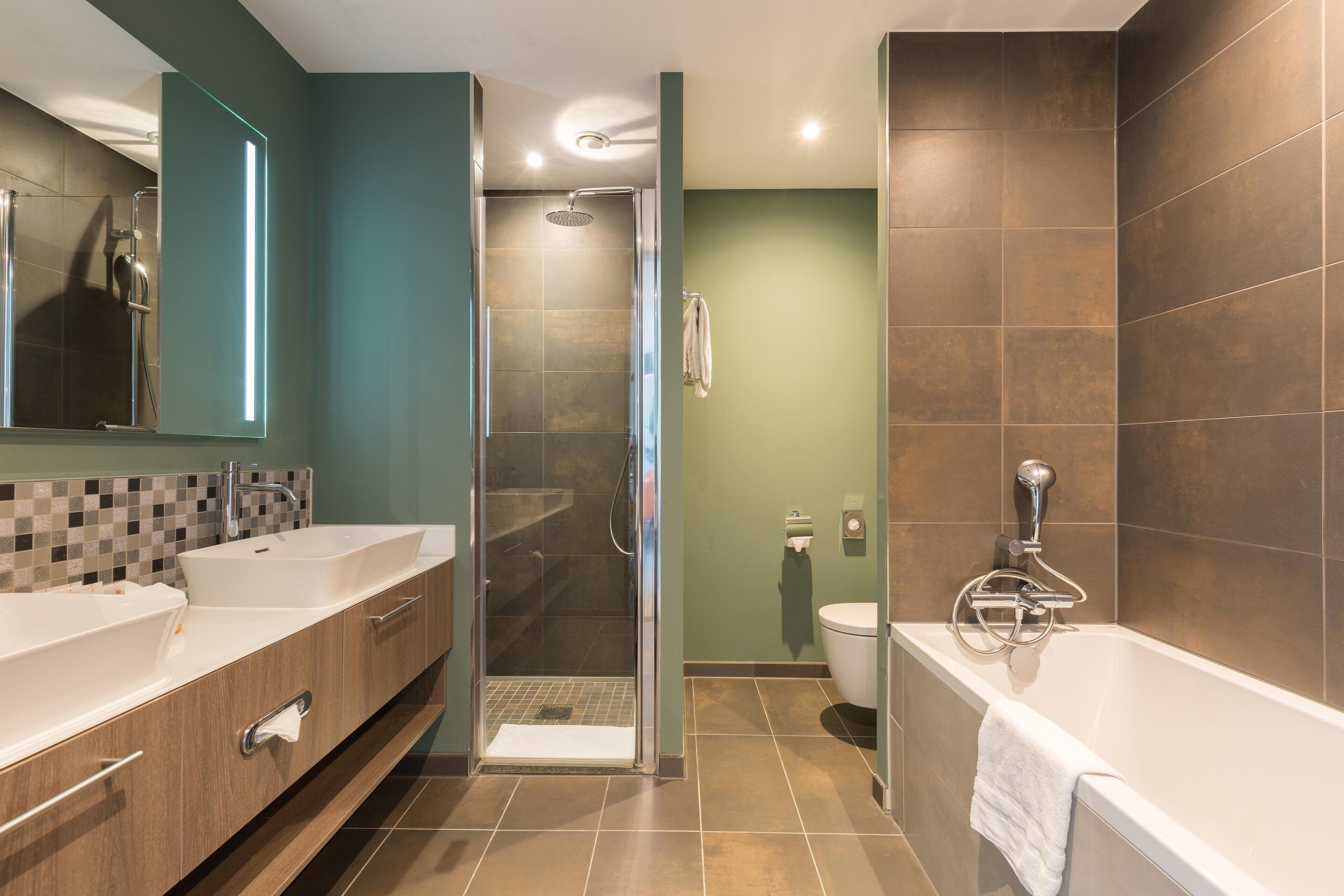 A modern bathroom with a walk-in shower, a bathtub, and a toilet.
