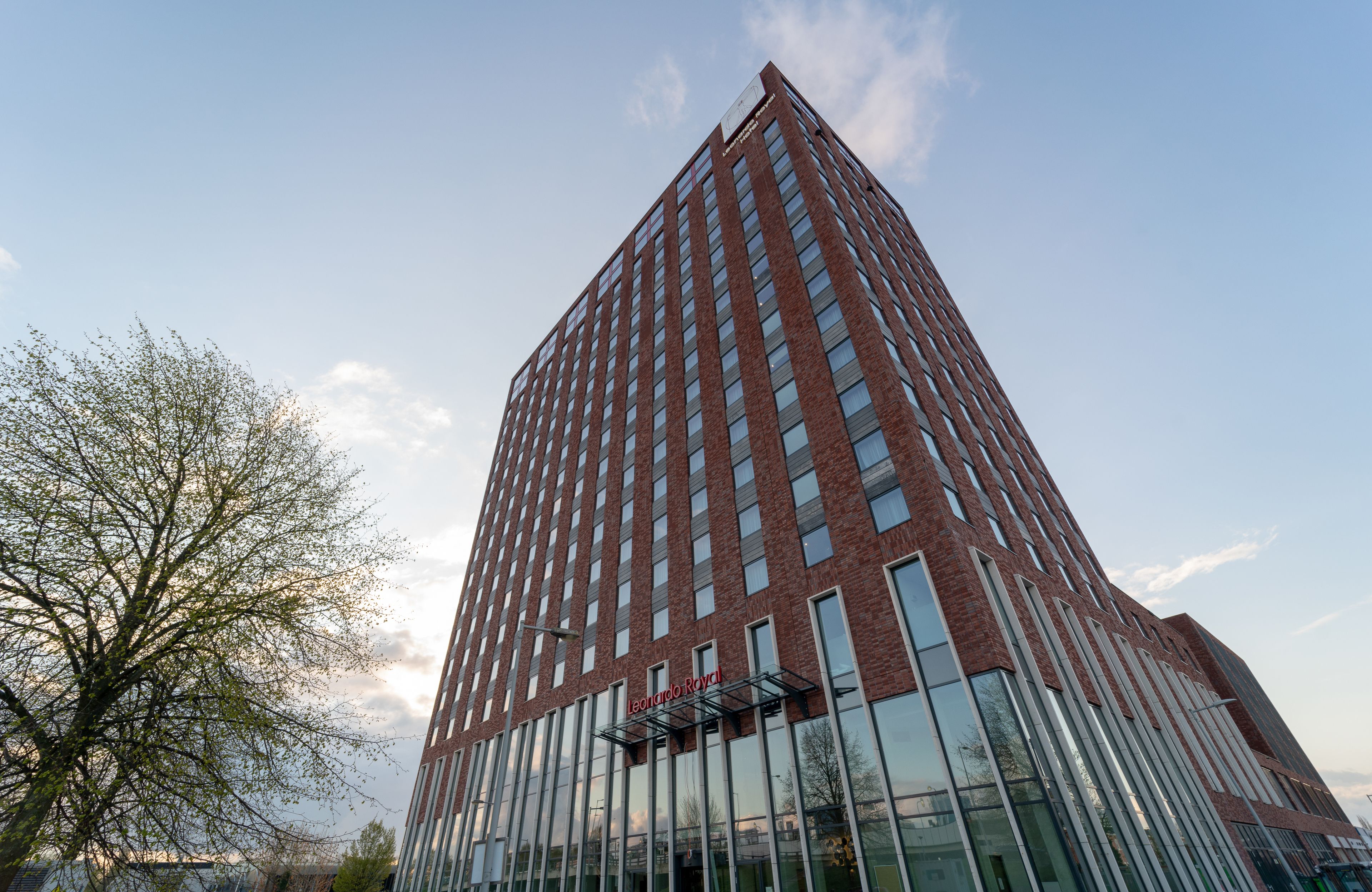 A tall, modern building with a red brick facade and large windows.