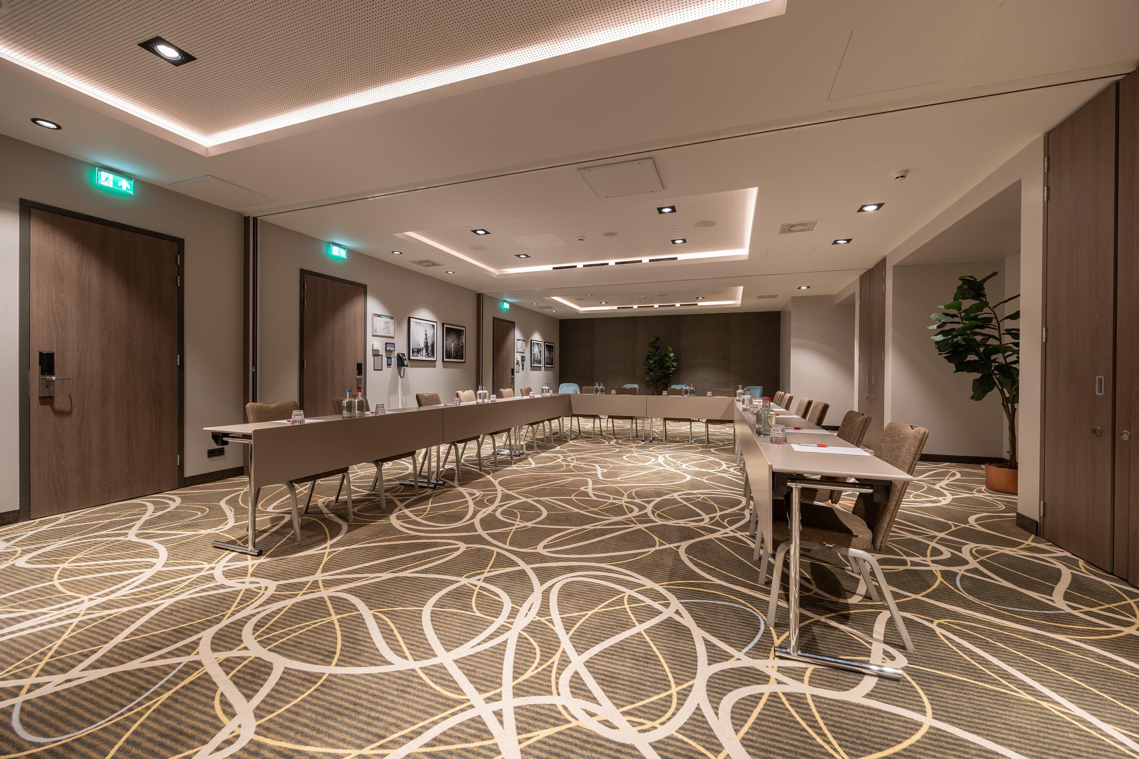 Une salle de conférence avec une longue table, des chaises et un tapis à motifs.