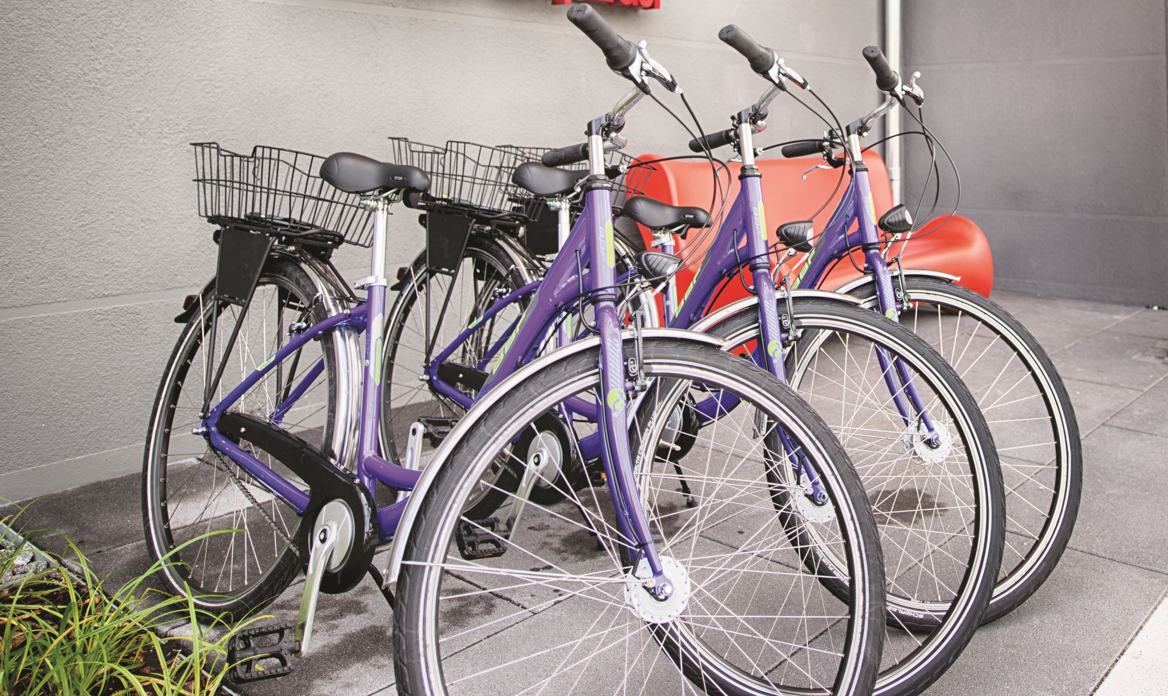 En rad cyklar står parkerade längs en vägg.