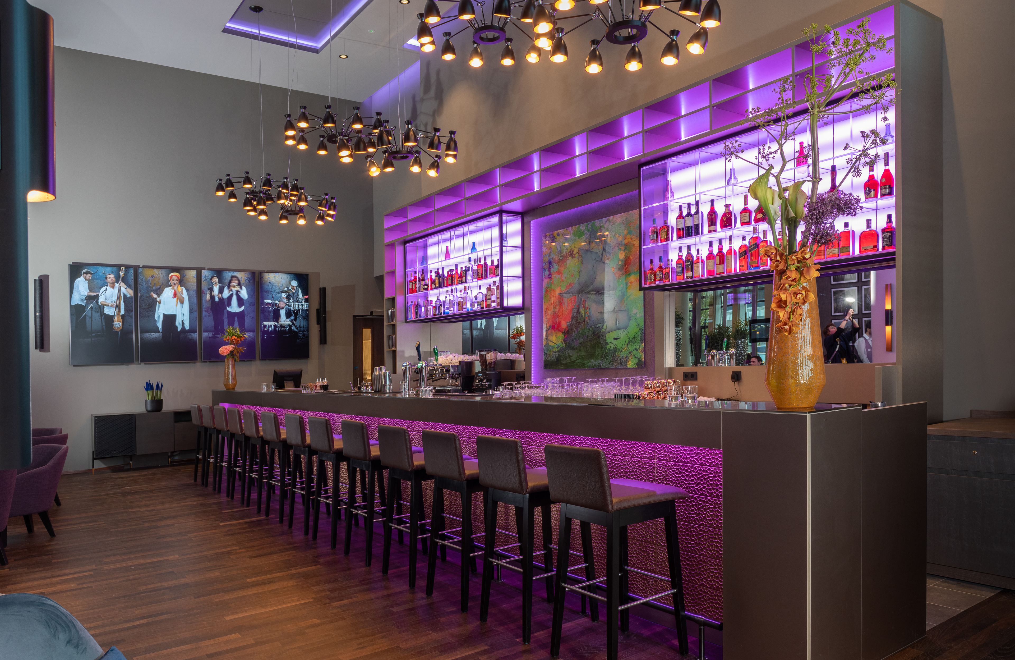 A modern bar area with a long counter, bar stools, and a large decorative vase.