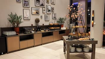 Een moderne hotel lobby met een buffetgedeelte, kunstwerken in lijsten aan de muren en potplanten.