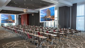A conference room with rows of tables and chairs, large windows, and a modern ceiling design.