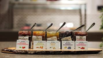 Variedad de conservas de frutas sobre una tabla de madera, con etiquetas que indican sabores como fresa, tarta de manzana, pera, arándano y frambuesa.