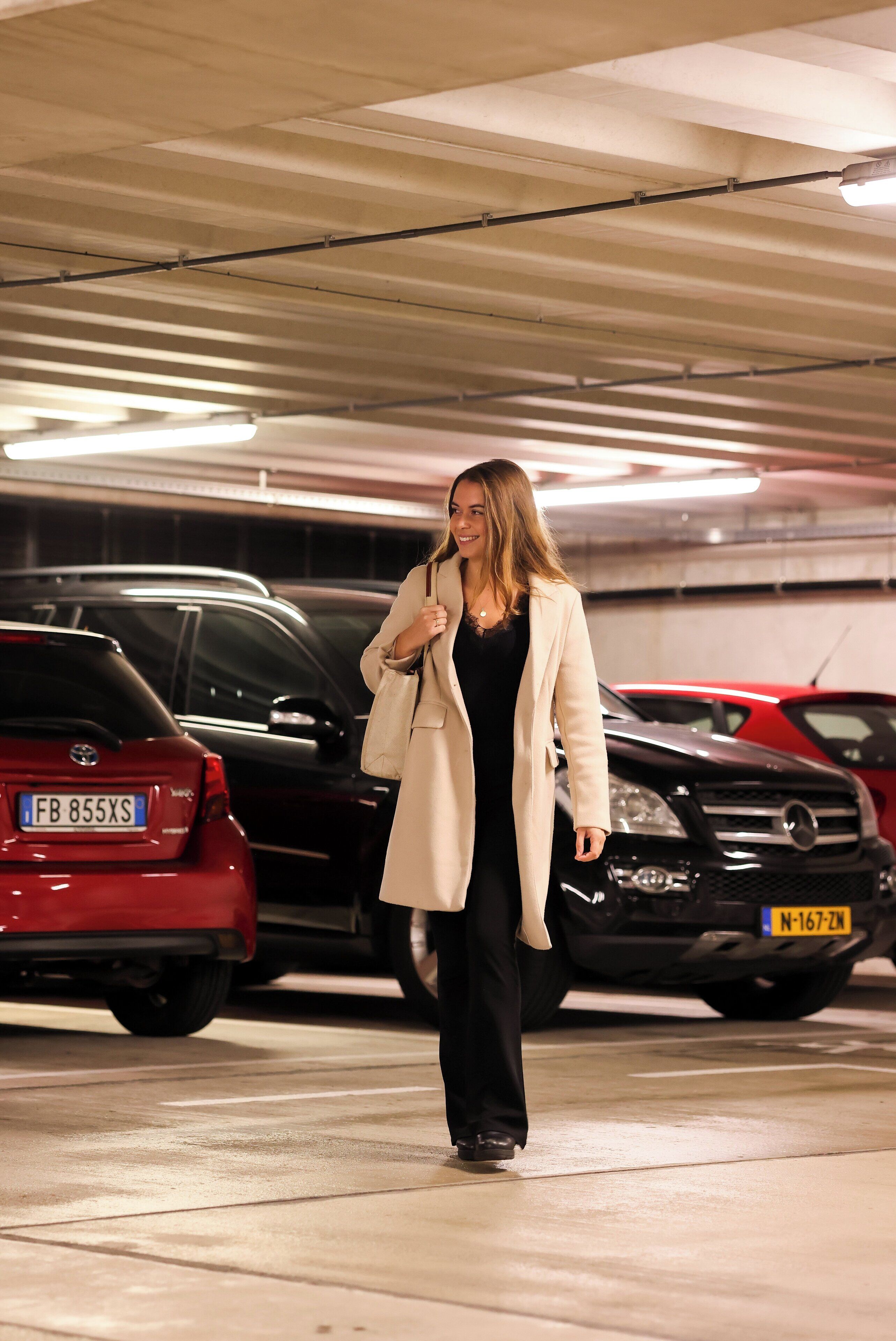 A person walking in a parking garage with cars parked around.
