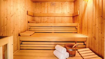 Una sauna in legno con panche e un catino di legno con un asciugamano.