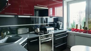 Una cocina moderna con gabinetes rojos, electrodomésticos de acero inoxidable y una ventana con plantas.