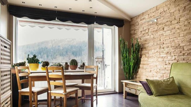 Una habitación con una mesa de comedor, sillas, un sofá y un amplio ventanal con vistas a la montaña.