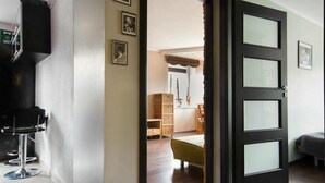 Un interior moderno con una puerta de marco negro, una zona de bar con un taburete y una cama al fondo.