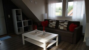 Sala de estar com mesa de centro branca, sofá marrom com almofadas listradas e estante branca.