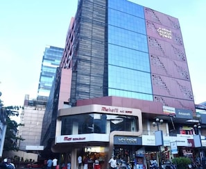A modern building with a glass facade and a sign for 'Amahath.' - Alhind Calicut Tower (Kozhikode)