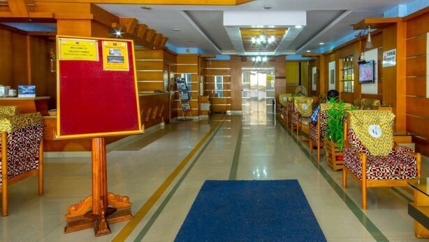 A hotel lobby with a reception desk, seating area, and a blue carpet. - Alhind Calicut Tower (Kozhikode)