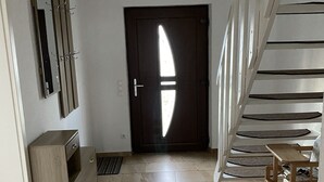 A modern interior with a wooden cabinet, a mirror, a staircase, and a door with a unique light design. - Ferienhaus Netzelkow am Achterwasser, Usedom, Baltic Sea, with WiFi, family-friendly (Lütow OT Netzelkow)