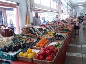 Un puesto de mercado con diversas frutas y verduras exhibidas en cestas y cajas.