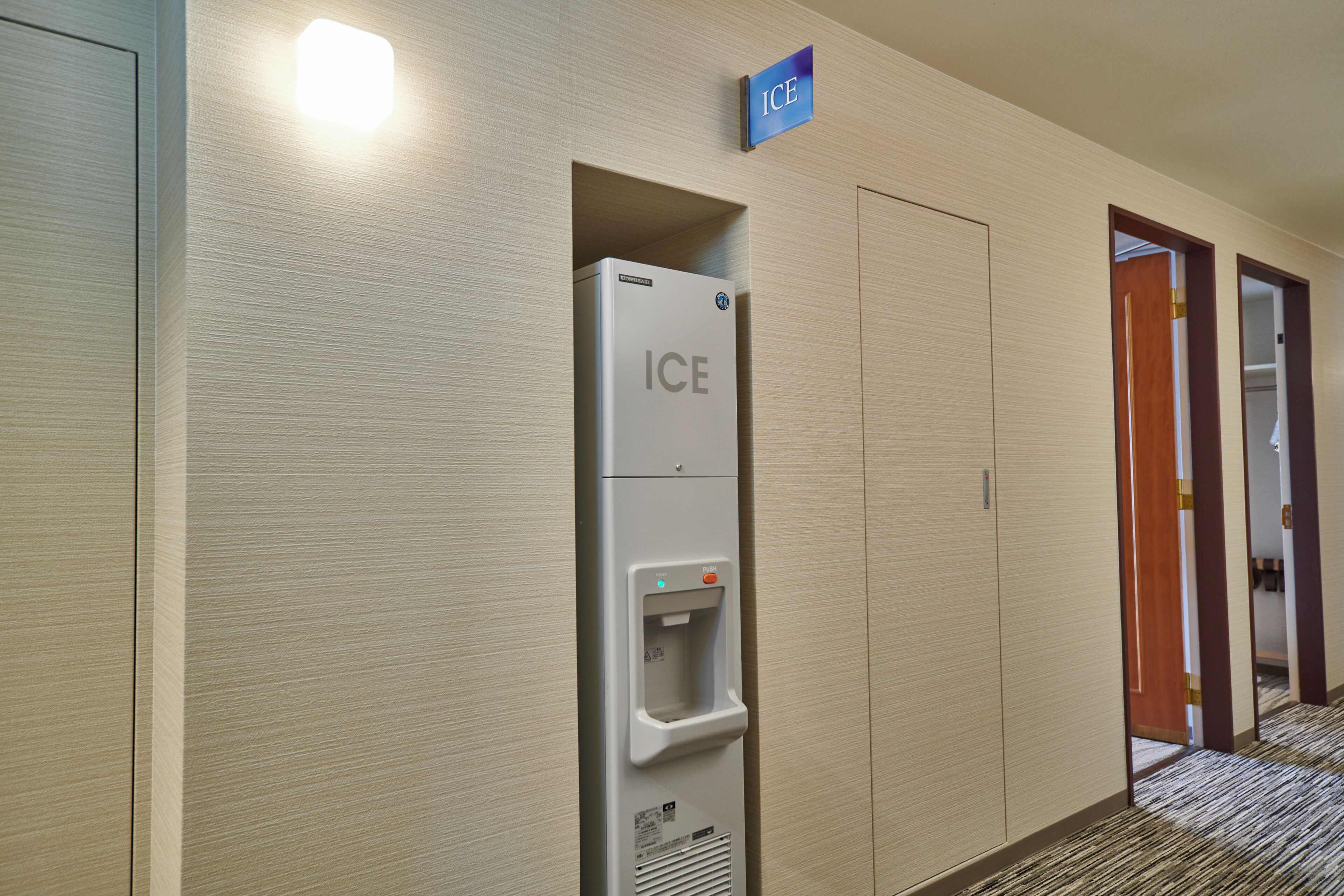 A corridor with a water dispenser labeled 'ICE' and a sign indicating the ice room.