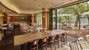 Un amplio comedor interior con mesas y sillas de madera, grandes ventanales que ofrecen vistas al exterior y un diseño de techo moderno.