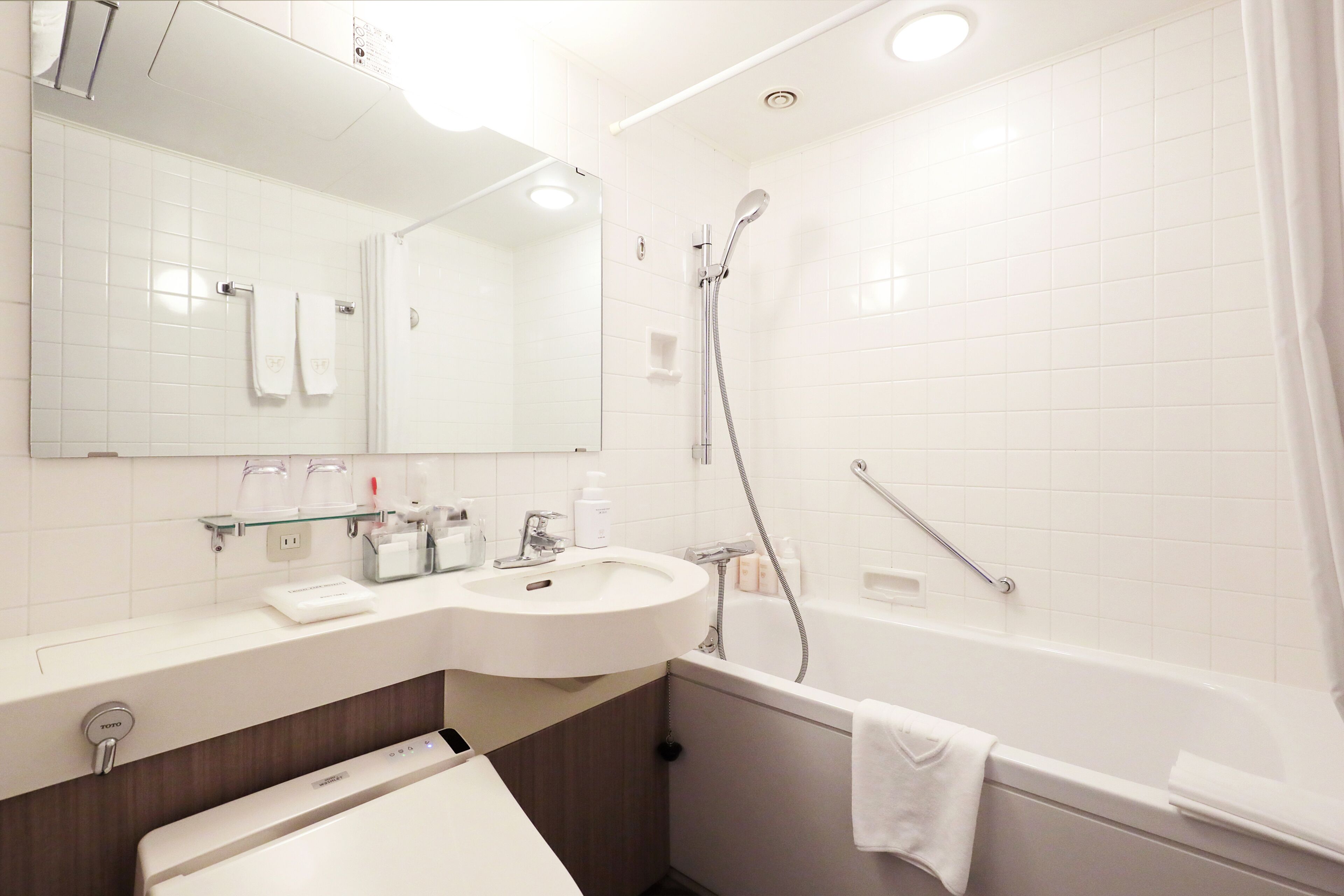 A modern bathroom with a white sink, mirror, and bathtub.