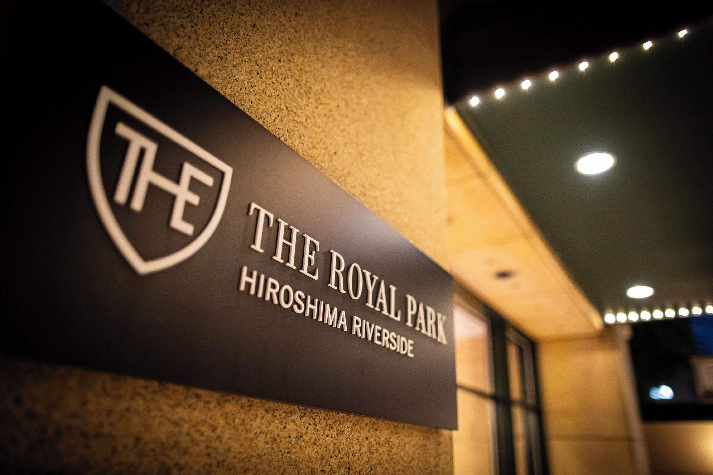 Schild mit dem Schriftzug 'The Royal Park' und einem Wappen, angebracht an einer strukturierten Wand.